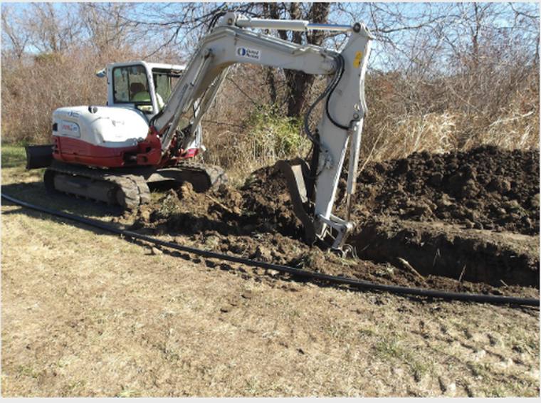 Excavator trenching for a buried utility line